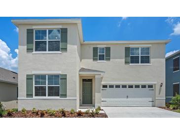 Two-story home with a white exterior, green shutters, a two-car garage, and a well-maintained front yard at 699 Griffon Ave, Lake Alfred, FL 33850