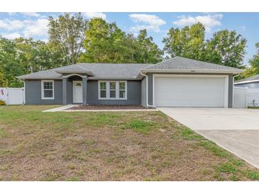 Charming single-story home featuring gray stucco, a two-car garage, and a well-maintained front lawn at 7101 Se 124Th St, Belleview, FL 34420
