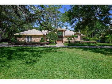Charming brick home with mature trees, manicured landscaping, and a welcoming front entrance at 725 Bear Creek Cir, Winter Springs, FL 32708