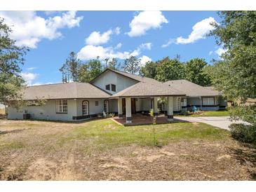 Stately home with a welcoming front porch and lush landscaping against a partly cloudy sky at 16500 Quarter Horse Ct, Montverde, FL 34756