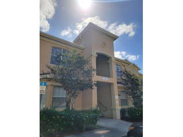 Inviting exterior of a two-story condo with a beige facade, front entry, and beautiful shrubbery at 204 Terrace Ridge Cir # 204, Davenport, FL 33896