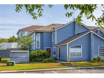 Charming two-story townhouse with blue siding, manicured lawn, and convenient parking spaces at 242 Coco Plum Dr, Davenport, FL 33897