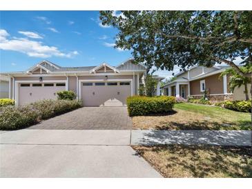 Charming tan home featuring a two-car garage and a beautifully paved driveway and walkway at 2423 Datura Loop, St Cloud, FL 34772