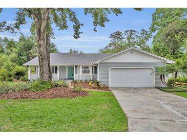 Charming single-story home with a well-manicured lawn, mature tree, and an attached two-car garage at 2610 Cloudcroft Dr, Apopka, FL 32703