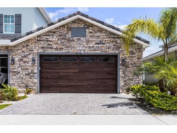Exterior stone garage with modern wood door, pavers, and well-maintained landscaping at 3078 Isles Way, New Smyrna Beach, FL 32168