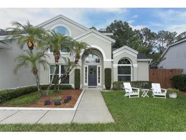 Charming home featuring well-manicured landscaping, palm trees, and a welcoming front porch with seating at 3562 Gatlin Pl, Orlando, FL 32812