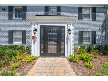 Inviting front entrance featuring a black door, brick walkway, and well-maintained landscaping at 130 Lewfield Cir # 130, Winter Park, FL 32792