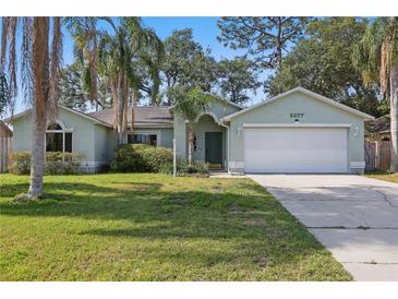 Charming single-story home featuring a well-manicured lawn, two car garage and lush tropical landscaping at 2277 Clearwater Dr, Deltona, FL 32738