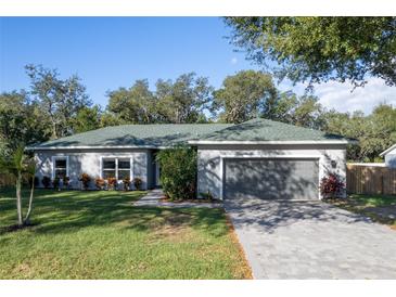 Charming single-story home with a gray exterior, a well-manicured lawn, and a paved driveway leading to a two-car garage at 2314 Pennsylvania Ave, Oviedo, FL 32765