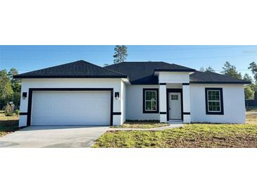 Charming single-story home featuring a two-car garage, white exterior, and black trim at 273 Marion Oaks Golf Rd, Ocala, FL 34473