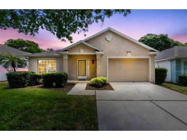 Charming single-story home featuring a well-manicured lawn, mature landscaping and an attached two-car garage at 3661 Kingswood Ct, Clermont, FL 34711