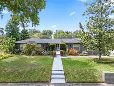 Charming single-story home with a manicured lawn, mature trees, and inviting walkway with gated entry at 4118 Teriwood Ave, Orlando, FL 32812