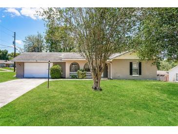 Charming single-story home featuring a well-maintained lawn, a tree, and an attached two-car garage at 845 N Ludlum Dr, Deltona, FL 32725