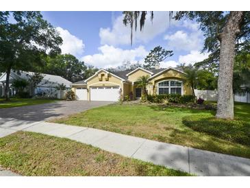 Charming yellow home with a three-car garage, lush lawn and mature landscaping at 1006 Hanging Vine Pt, Longwood, FL 32750