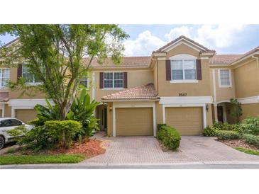 Charming townhome featuring a brick driveway, tile roof, and lush landscaping at 3567 Shallot Dr # 103, Orlando, FL 32835