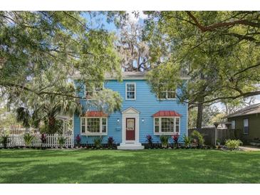 Charming blue two-story home with manicured lawn and beautiful mature trees creating curb appeal at 1000 Pennsylvania Ave, Lakeland, FL 33803