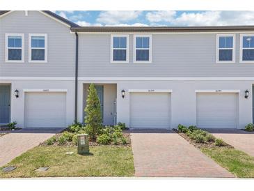 Charming townhome exterior features attached garages, brick driveways and walkways, and professionally landscaped lawns at 16399 Bird Of Paradise Ave, Clermont, FL 34714