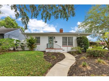 Charming home featuring a curved walkway to the front door, mature landscaping, and a brick facade at 1845 Delaney Ave, Orlando, FL 32806