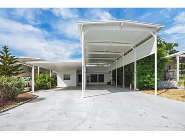 Bright white home featuring a covered carport, mature landscaping, and blue skies at 367 Par Pines Blvd, Davenport, FL 33837
