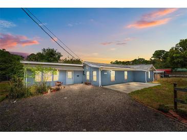 Charming single-story home with gravel driveway, blue siding, and a peaceful residential setting at dusk at 55119 5Th St, Astor, FL 32102