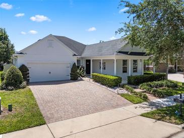 Charming single-story home featuring a manicured lawn, brick driveway, and attached two-car garage at 11407 Wakeworth St, Orlando, FL 32836