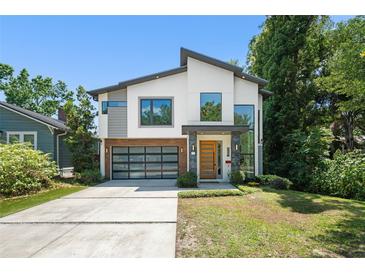 Stunning modern home featuring a glass garage door, crisp white accents, and professional landscaping at 1624 E Livingston St, Orlando, FL 32803