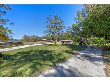 Charming exterior of home with mature trees, long driveway, and lush green lawn at 20 Lido Rd, Winter Springs, FL 32708