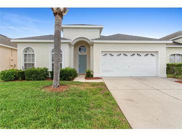 Charming single-story home with a well-manicured lawn and a two-car garage on a sunny day at 2263 Wyndham Palms Way, Kissimmee, FL 34747