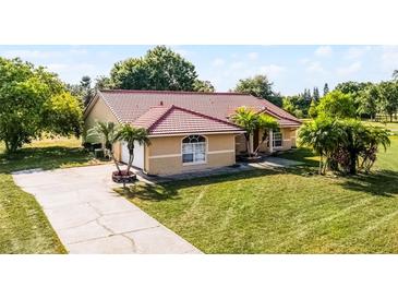 Charming single-story home with a well-manicured lawn, tiled roof, and a long driveway at 2726 La Alameda Ave, Kissimmee, FL 34746