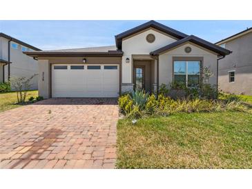 Charming single-story home featuring a brick driveway, a two-car garage, and well-maintained landscaping at 3128 Oxbow Ct, Harmony, FL 34773