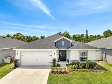 Charming single-story home featuring a manicured lawn, two-car garage, and inviting front entrance at 62 Polermo Ave, St Cloud, FL 34771