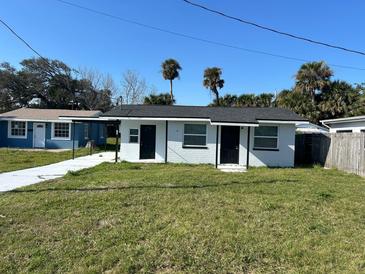 Charming white home with dark doors, a covered patio, and a freshly painted driveway at 73 Brooks Dr, Ormond Beach, FL 32176