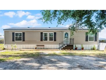 Charming single-story home with a front porch, neutral siding, and black shutters against a backdrop of blue skies at 8218 Pine Island Rd, Clermont, FL 34711
