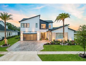 Modern two-story home with a glass-door garage, manicured lawn, and a beautiful brick driveway at 9877 Laurel Berry Dr, Orlando, FL 32827