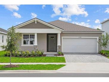 Charming single-story home featuring a two-car garage, manicured lawn, and inviting front entrance with stone accents at 13248 Pergola Ave, Orlando, FL 32832