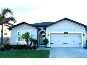 Charming home featuring a two-car garage, well-manicured lawn, and inviting entryway with decorative features at 13299 Serene Valley Dr, Clermont, FL 34711
