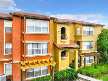 Exterior view of multi-Gathering home with orange and yellow stucco and clay tile roof at 5164 Conroy Rd # 1526, Orlando, FL 32811