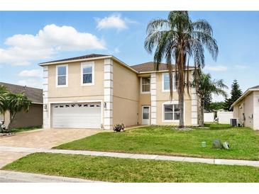 Charming two-story home featuring a manicured lawn, brick driveway, and well-maintained landscaping at 13054 Prairie Meadows Dr, Orlando, FL 32837