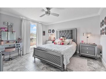 Cozy bedroom features gray walls, tile floor, and plush bedding with a ceiling fan, natural light, and a vanity at 1450 Belfiore Way, Windermere, FL 34786