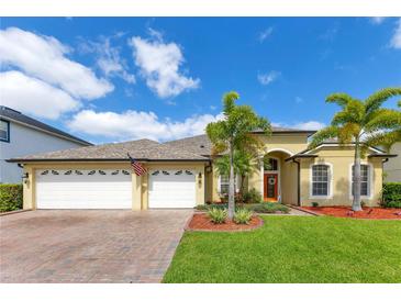 Charming single-Gathering home featuring a three-car garage, landscaped yard, and tropical palm trees at 16313 Birchwood Way, Orlando, FL 32828