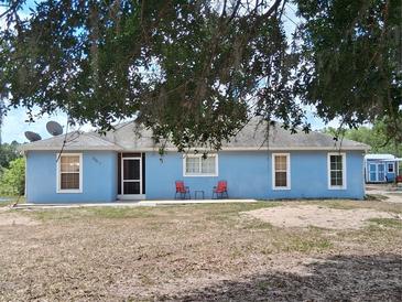 Charming single-story home with a light blue exterior, complemented by two red chairs near the entrance at 25618 Fishermans Rd, Paisley, FL 32767