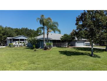Landscaped yard with charming one-story home, detached garage, and RV parking on a sunny day at 4170 Packard Ave, St Cloud, FL 34772