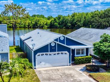 Charming blue home boasts a well-maintained lawn, attached garage and lovely lake view at 148 Meadow Blvd, Sanford, FL 32771