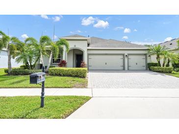 Inviting exterior with well-manicured lawn, lush landscaping, and a three car garage at 15366 Sandfield Loop, Winter Garden, FL 34787