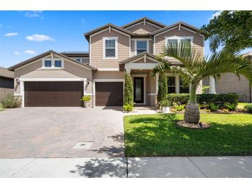 Charming two-story home featuring a three-car garage, landscaped yard, and a paver driveway under a sunny sky at 2614 Mead Ave, St Cloud, FL 34771