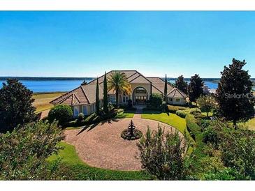 Stunning lakefront home with lush landscaping, circular driveway and beautiful architectural details at 8250 Cherry Lake Rd, Groveland, FL 34736