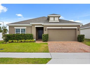 Charming single-story home featuring a well-maintained lawn, neat landscaping, and a brick-paved driveway at 849 Avenal Ln, Davenport, FL 33837