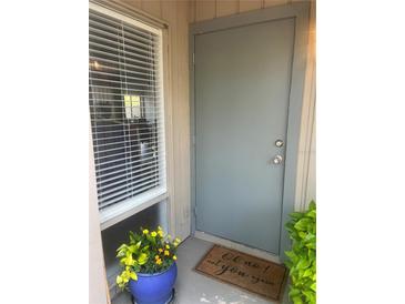 Welcoming front entrance with a charming doormat, window with blinds and a vibrant potted plant at 112 Crown Oaks Way # 112, Longwood, FL 32779