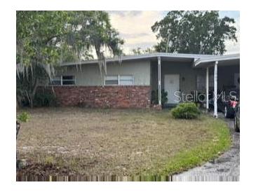 Single-story home featuring a carport, neutral color palette, brick accents, and a spacious front yard at 1909 Edwin Blvd, Winter Park, FL 32792