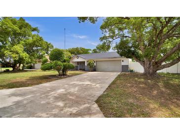Charming single-story home boasts a long driveway, a two-car garage, and mature landscaping at 1965 Greenview Dr, Deltona, FL 32725